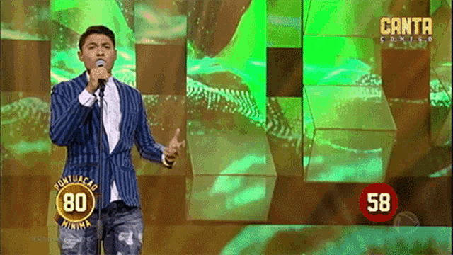 a man singing into a microphone in front of a green background that says canta