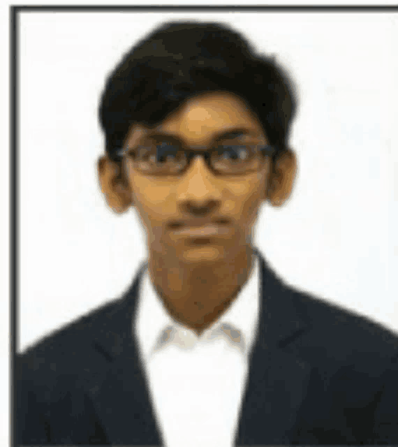 a young boy wearing glasses and a suit is posing for a picture .