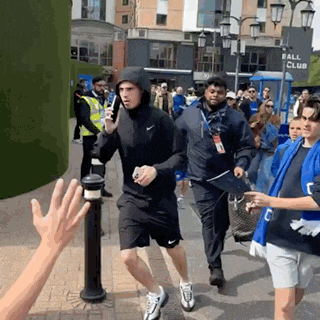 a group of people are walking down a street with a sign that says ball club in the background
