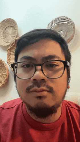 a man wearing glasses and a red shirt is making a funny face