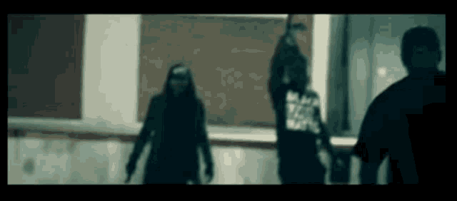 a group of people are standing in a dark room and one of them is wearing a black shirt that says ' black lives matter '