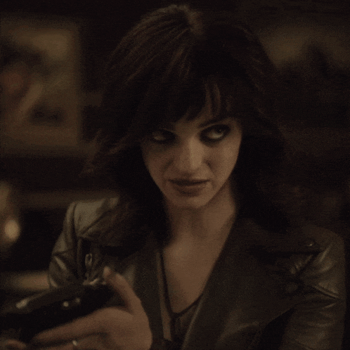a woman wearing a leather jacket and a watch looks at her phone
