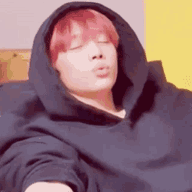a man with red hair is wearing a black hoodie and making a face .