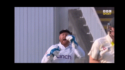 a man wearing a cinch shirt wipes his face with his gloves