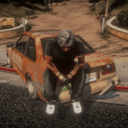 a man sits on the trunk of a rusted car with a license plate that says d6642