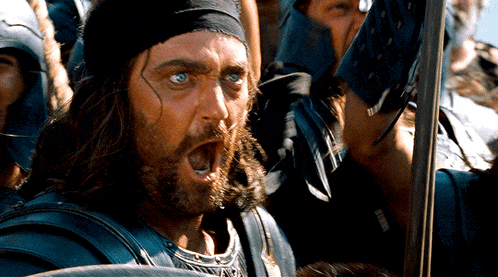 a man with a bandana on his head is holding a sword and screaming
