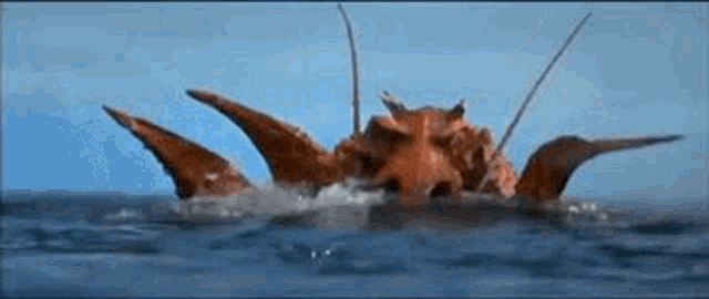 a monster is swimming in the ocean with its wings outstretched .