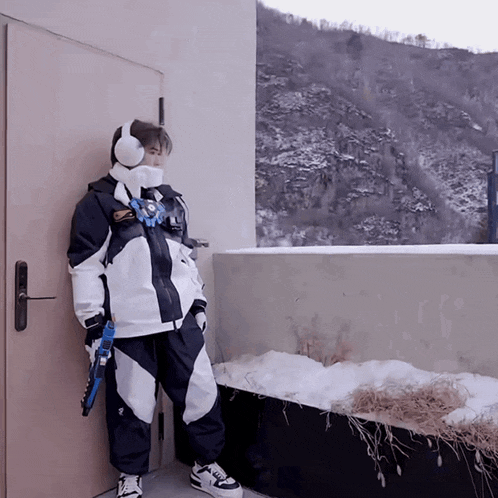 a person standing in front of a door wearing headphones and a jacket that says ' salomon ' on it