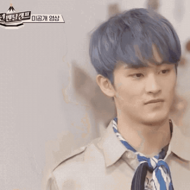 a young man with blue hair is making a funny face .