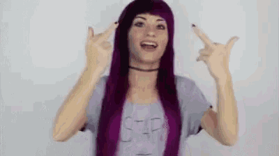 a woman with purple hair and a choker is making a peace sign .