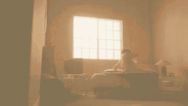 a woman laying on a bed in a room with a window