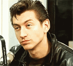 a man in a black leather jacket is sitting in front of a microphone