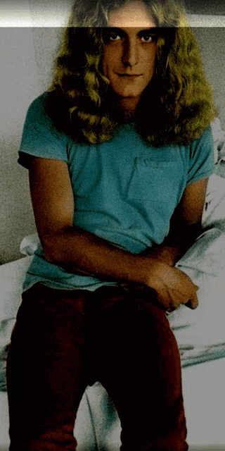 a man with long blonde hair is wearing a blue shirt and red jeans