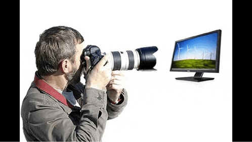 a man is taking a picture with a camera and a computer monitor behind him .