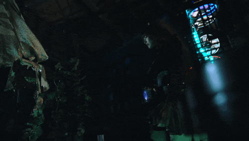 a person standing in a dark room with a blue light shining on them
