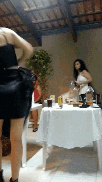 a woman in a black dress stands in front of a table with a white tablecloth
