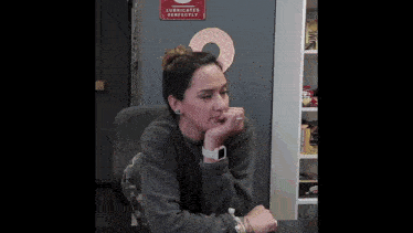 a woman sits at a desk in front of a sign that says " lubricates perfectly "