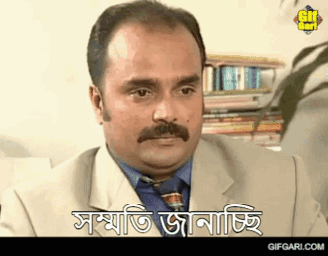 a man with a mustache is wearing a suit and tie and says " gifgari.com " on the bottom
