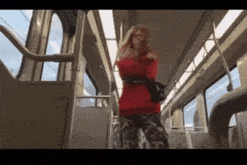 a woman in a red sweater is standing on a train with her arms crossed