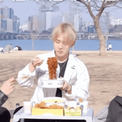 a man in a white coat is eating noodles from a bowl with chopsticks
