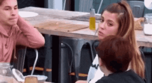 a group of people are sitting at a table talking .