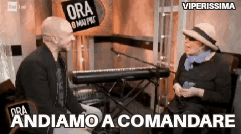 a man and a woman are sitting in front of a keyboard talking to each other .