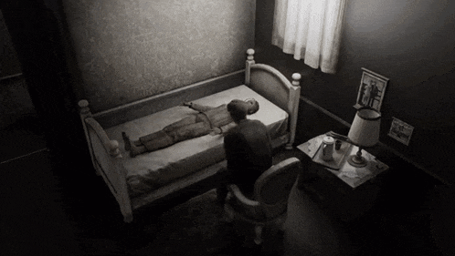 a black and white photo of a man laying in a bed next to a nightstand