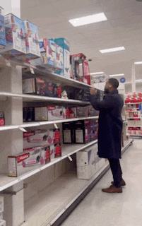 a man in a black coat is standing in front of a shelf that has a red box that says ' barbie '