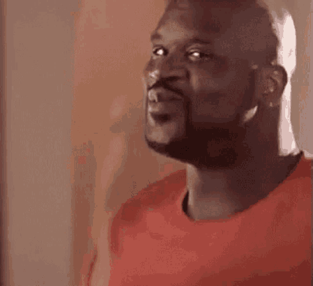 a bald man with a beard and mustache is wearing a red shirt and making a funny face .