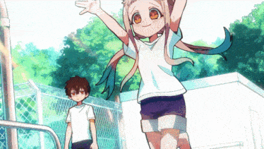 a boy and a girl are standing in front of a fence .