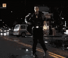 a man in a suit is walking down a street at night