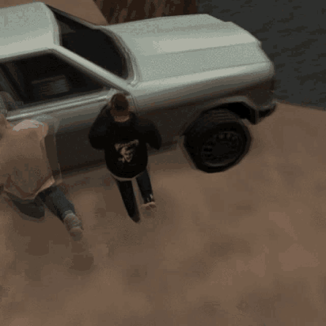 a man wearing a black shirt with a skull on it stands next to a car