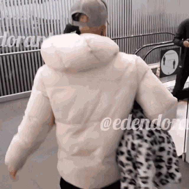 a woman in a white jacket is walking down an escalator with the words edendorn written on her back