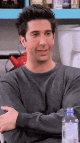 a man with his arms crossed is smiling with a bottle of water in front of him