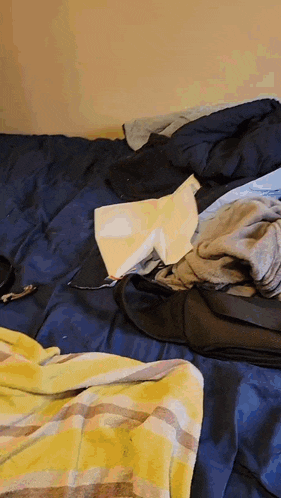 a pile of clothes on a bed with a yellow blanket
