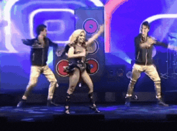 a group of people are dancing on a stage in front of a large speaker