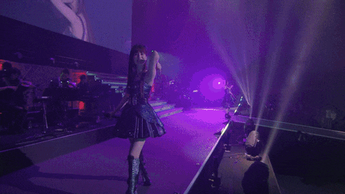 a woman in a black dress points at the camera