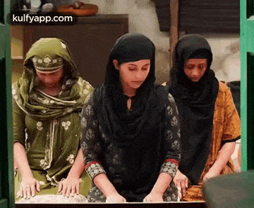 three women are standing next to each other in a kitchen .