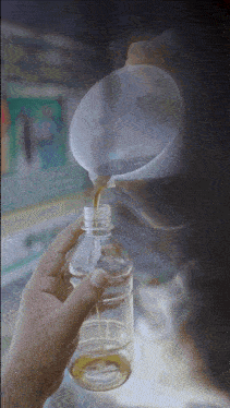 a person pouring liquid into a plastic bottle with a funnel