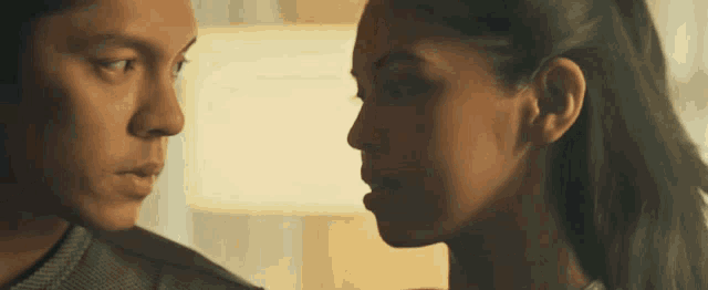 a man and a woman are looking at each other and their faces are very close together .