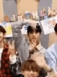 a group of people are standing next to each other in a room and giving the peace sign .