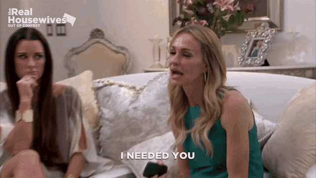 two women are sitting on a couch and one of them is holding a remote control and says " i needed you "