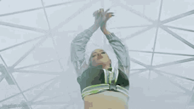 a woman in a neon outfit is dancing in a room with a white ceiling .