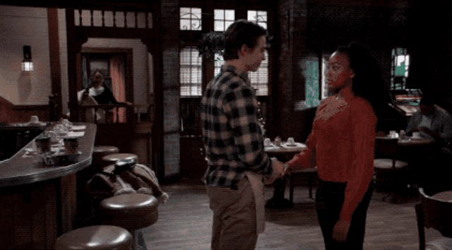 a man and a woman standing in a restaurant holding hands