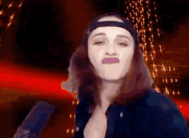 a woman wearing a baseball cap is making a funny face while standing in front of a microphone .