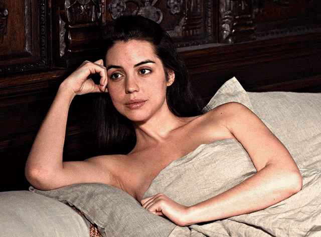 a naked woman laying on a bed with her hand on her face