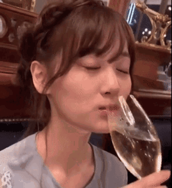 a young woman is drinking from a glass of wine .
