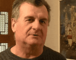 a man in a black sweater is standing in front of a painting