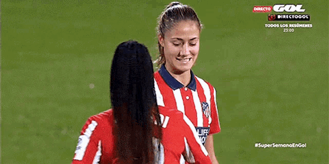 two female soccer players are talking to each other on the field