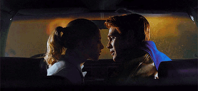 a man and woman are kissing in a car